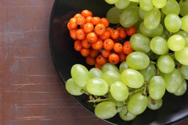 Yeşil üzüm, mavi Erik ve turuncu üvez meyveleri retro tarzı tasarımcısında için siyah bir plaka üzerinde