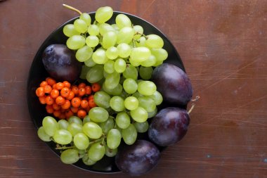 Yeşil üzüm, mavi Erik ve turuncu üvez meyveleri retro tarzı tasarımcısında için siyah bir plaka üzerinde