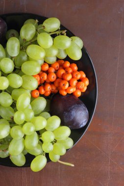 Yeşil üzüm, mavi Erik ve turuncu üvez meyveleri retro tarzı tasarımcısında için siyah bir plaka üzerinde