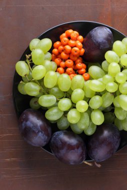 Yeşil üzüm, mavi Erik ve turuncu üvez meyveleri retro tarzı tasarımcısında için siyah bir plaka üzerinde