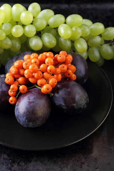 Yeşil üzüm, mavi Erik ve turuncu üvez meyveleri retro tarzı tasarımcısında için siyah bir plaka üzerinde