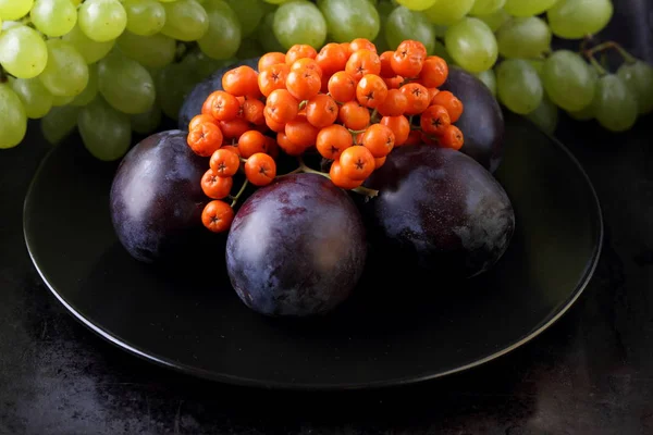 Yeşil üzüm, mavi Erik ve turuncu üvez meyveleri retro tarzı tasarımcısında için siyah bir plaka üzerinde