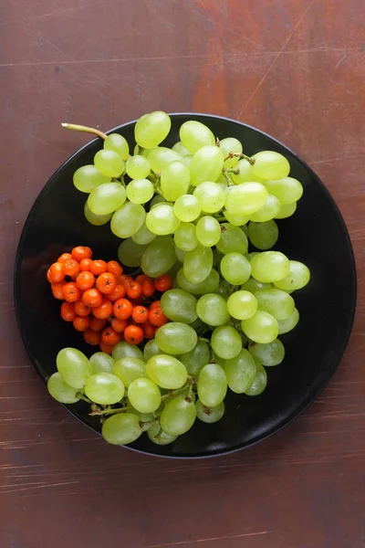 Yeşil üzüm, mavi Erik ve turuncu üvez meyveleri retro tarzı tasarımcısında için siyah bir plaka üzerinde