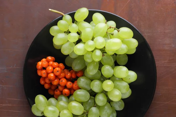 Uvas verdes, ameixas azuis e bagas rowan laranja em uma placa preta para designer em estilo retro — Fotografia de Stock