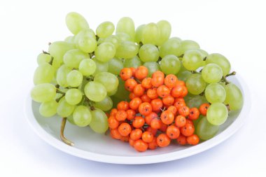 Yeşil üzüm ve minimalizm tarzı bir plaka üzerinde beyaz bir arka planda turuncu ashberry