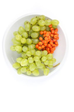 Yeşil üzüm ve minimalizm tarzı bir plaka üzerinde beyaz bir arka planda turuncu ashberry