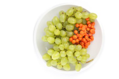 Yeşil üzüm ve minimalizm tarzı bir plaka üzerinde beyaz bir arka planda turuncu ashberry