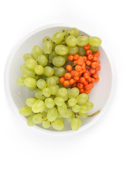 Yeşil üzüm ve minimalizm tarzı bir plaka üzerinde beyaz bir arka planda turuncu ashberry