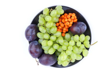 Yeşil üzüm, rowan ve minimalizm tarzı siyah bir plaka üzerinde beyaz bir arka plan üzerinde büyük Erik