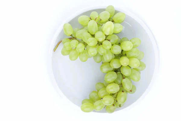 Uvas verdes em um fundo branco em uma chapa no estilo de minimalismo — Fotografia de Stock