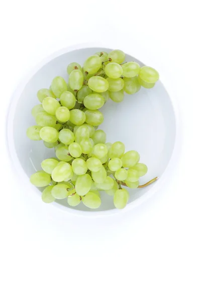 Uvas verdes em um fundo branco em uma chapa no estilo de minimalismo — Fotografia de Stock