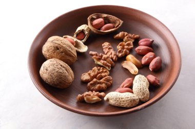 Ceviz ve beyaz bir arka plan üzerinde kahverengi kil tabakta fıstık