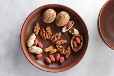 Ceviz ve beyaz bir arka plan üzerinde kahverengi kil tabakta fıstık