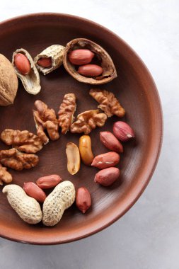 Ceviz ve beyaz bir arka plan üzerinde kahverengi kil tabakta fıstık