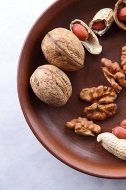 Ceviz ve beyaz bir arka plan üzerinde kahverengi kil tabakta fıstık