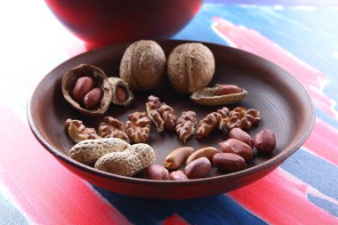 Ceviz ve pop sanat arka plan üzerinde kahverengi kil tabakta fıstık