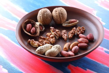 Ceviz ve pop sanat arka plan üzerinde kahverengi kil tabakta fıstık