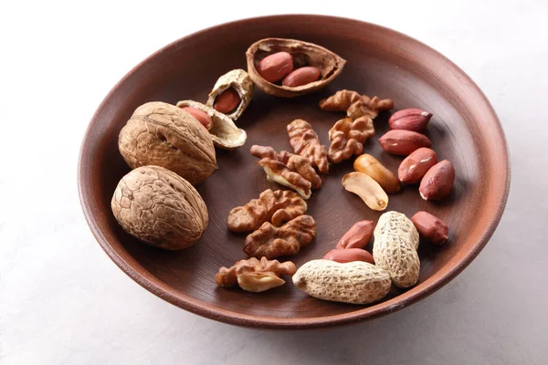 Ceviz ve beyaz bir arka plan üzerinde kahverengi kil tabakta fıstık