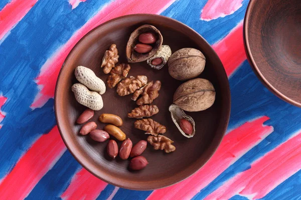 Ceviz ve pop sanat arka plan üzerinde kahverengi kil tabakta fıstık