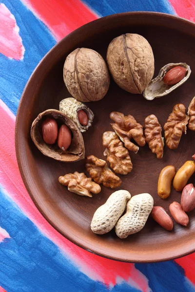 Ceviz ve pop sanat arka plan üzerinde kahverengi kil tabakta fıstık