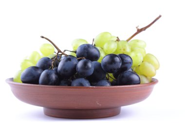 Bir kil plaka beyaz zemin üzerine yeşil ve mavi üzüm