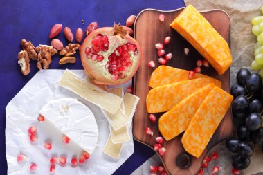Camembert peyniri, mermer peynir, farklı peynirler, koyu mavi üzüm, kırmızı nar, Yeşil üzüm, fıstık ve ceviz retro tarzı yazmak için boş bir yer ile ahşap bir gemide