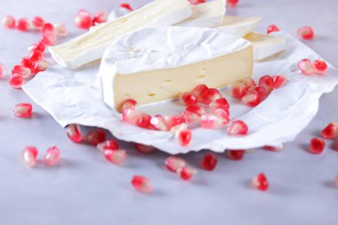 Camembert peyniri, peynir, peynir beyaz zemin üzerine nar taneleri ile bir sürü dilimlenmiş
