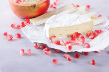Camembert peyniri, peynir, peynir beyaz zemin üzerine nar taneleri ile bir sürü dilimlenmiş