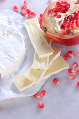 Camembert peyniri, peynir, peynir beyaz zemin üzerine nar taneleri ile bir sürü dilimlenmiş