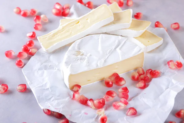 Camembert peyniri, peynir, peynir beyaz zemin üzerine nar taneleri ile bir sürü dilimlenmiş
