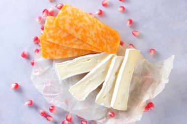 Camembert peyniri, dilimlenmiş peynir, turuncu peynir, peynir bir sürü. Yeşil üzüm ve beyaz zemin üzerine nar taneleri