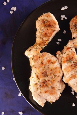 Biftek ahşap çatal, büyük tuz, baharat ve fıstık retro tarzı bir koyu mavi arka plan üzerinde siyah bir tabak ızgara ile