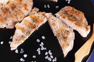 Biftek ahşap çatal, büyük tuz, baharat ve fıstık retro tarzı bir koyu mavi arka plan üzerinde siyah bir tabak ızgara ile