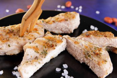 Biftek ahşap çatal, büyük tuz, baharat ve fıstık retro tarzı bir koyu mavi arka plan üzerinde siyah bir tabak ızgara ile