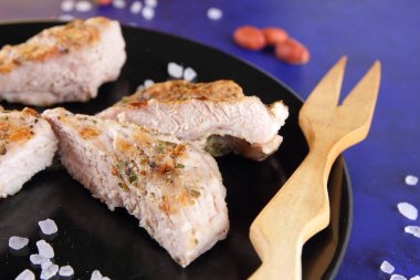 Biftek ahşap çatal, büyük tuz, baharat ve fıstık retro tarzı bir koyu mavi arka plan üzerinde siyah bir tabak ızgara ile