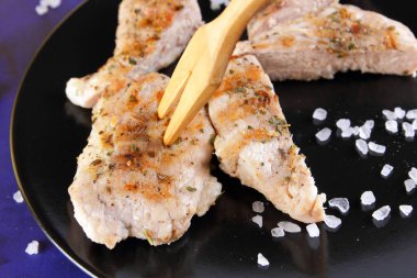 Biftek ahşap çatal, büyük tuz, baharat ve fıstık retro tarzı bir koyu mavi arka plan üzerinde siyah bir tabak ızgara ile