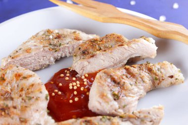 Biftek ızgara beyaz tabakta ahşap çatal, domates sosu, baharat ve retro tarzı koyu mavi zemin üzerine hardal taneleri ile