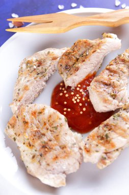 Biftek ızgara beyaz tabakta ahşap çatal, domates sosu, baharat ve retro tarzı koyu mavi zemin üzerine hardal taneleri ile