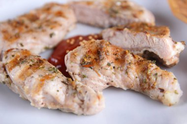 Biftek ızgara beyaz tabakta ahşap çatal, domates sosu, baharat ve retro tarzı koyu mavi zemin üzerine hardal taneleri ile