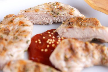 Biftek ızgara beyaz tabakta ahşap çatal, domates sosu, baharat ve retro tarzı koyu mavi zemin üzerine hardal taneleri ile