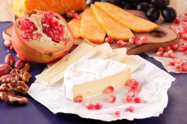 Camembert peyniri, mermer peynir, farklı peynirler, koyu mavi üzüm, kırmızı nar, Yeşil üzüm, fıstık ve ceviz ahşap oyun tahtası ile yazmak için boş bir yer