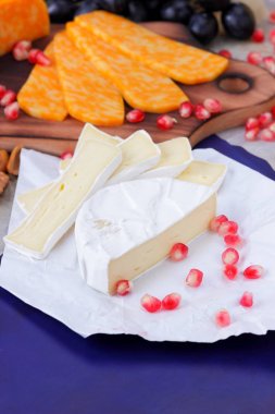 Camembert peyniri, mermer peynir, farklı peynirler, koyu mavi üzüm, kırmızı nar, Yeşil üzüm, fıstık ve ceviz ahşap oyun tahtası ile yazmak için boş bir yer