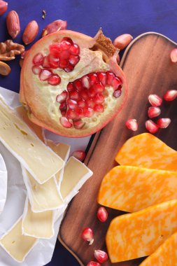 Camembert peyniri, mermer peynir, farklı peynirler, koyu mavi üzüm, kırmızı nar, Yeşil üzüm, fıstık ve ceviz ahşap oyun tahtası ile yazmak için boş bir yer
