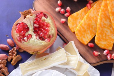Camembert peyniri, mermer peynir, farklı peynirler, koyu mavi üzüm, kırmızı nar, Yeşil üzüm, fıstık ve ceviz ahşap oyun tahtası ile yazmak için boş bir yer