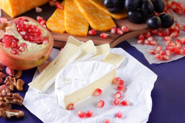 Camembert peyniri, mermer peynir, farklı peynirler, koyu mavi üzüm, kırmızı nar, Yeşil üzüm, fıstık ve ceviz ahşap oyun tahtası ile yazmak için boş bir yer