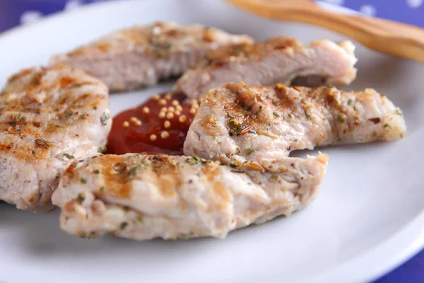 Biftek ızgara beyaz tabakta ahşap çatal, domates sosu, baharat ve retro tarzı koyu mavi zemin üzerine hardal taneleri ile