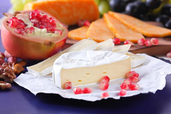 Camembert peyniri, mermer peynir, farklı peynirler, koyu mavi üzüm, kırmızı nar, Yeşil üzüm, fıstık ve ceviz ahşap oyun tahtası ile yazmak için boş bir yer