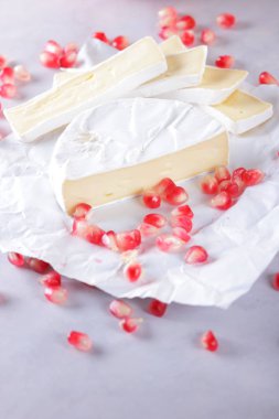 Camembert peyniri, peynir, peynir beyaz zemin üzerine nar taneleri ile bir sürü dilimlenmiş