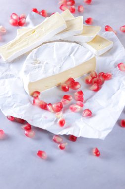 Camembert peyniri, peynir, peynir beyaz zemin üzerine nar taneleri ile bir sürü dilimlenmiş