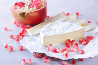 Camembert peyniri, peynir, peynir beyaz zemin üzerine nar taneleri ile bir sürü dilimlenmiş